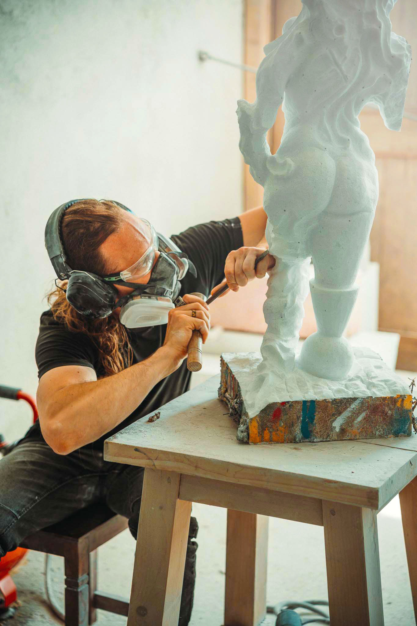 Jonas Eideloth arbeitet mit Hammer und Meißel an einer hellen Skulptur